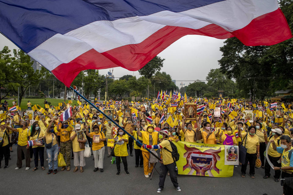 Supporters of the Thai monarchy display images of King Maha Vajiralongkorn, Queen Suthida, late King Bhumibol Adulyadej and wave a giant national flag during a rally at Lumphini park in central Bangkok, Thailand Tuesday, Oct. 27, 2020. Hundreds of royalists gathered to oppose pro-democracy protesters' demands that the prime minister resign, constitution be revised and the monarchy be reformed in accordance with democratic principles. (AP Photo/Gemunu Amarasinghe)