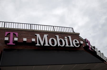 People pass by a T-Mobile store in the Brooklyn borough of New York June 4, 2015. REUTERS/Brendan McDermid