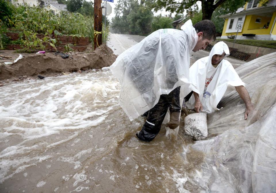 People use sand bags and plastic sheeting to prevent a berm from washing out as water rise in heavy rain in Boulder, Colorado