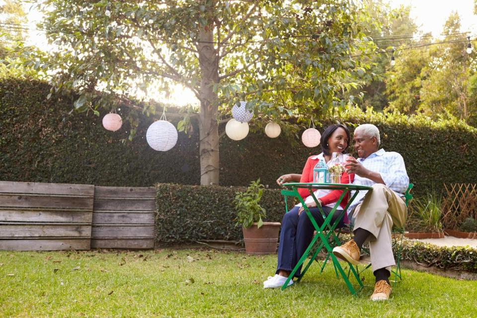 Smiling couple sitting at the table in their backyard.