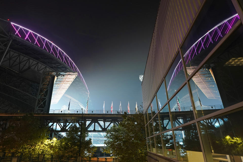 Smoke from wildfires is seen in the air as lights from T-Mobile Park, left, are reflected in a window of CenturyLink Field, right, following an MLS soccer match between the Seattle Sounders and the San Jose Earthquakes, Thursday, Sept. 10, 2020, in Seattle. A huge plume of smoke from fires in Oregon and California moved into the Seattle area Thursday night, leading to warnings of unhealthy air quality in many areas of the state through the weekend. (AP Photo/Ted S. Warren)