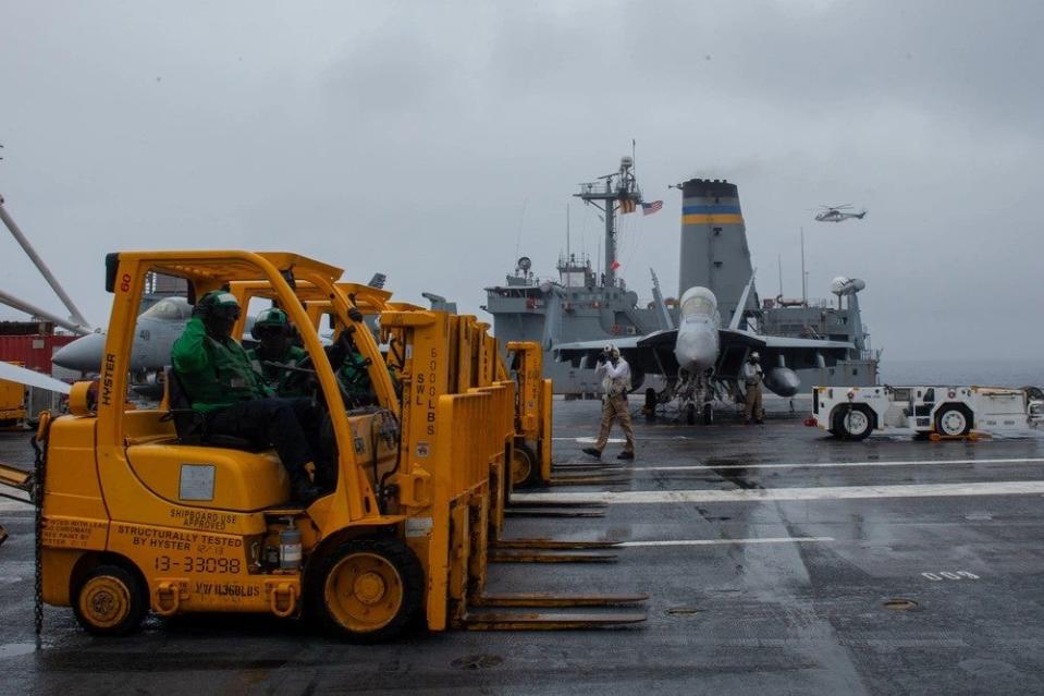 Sailors stand by to receive pallets on the flight deck of the U.S. Navy’s only forward-deployed aircraft carrier, USS <em>Ronald Reagan</em> (CVN 76), during a vertical replenishment-at-sea with Military Sealift Command dry cargo ship, USNS <em>Charles Drew</em> (T-AKE 10), in the Philippine Sea, May 23. (U.S. Navy photo by Mass Communication Specialist 3rd Class Kazia Ream)