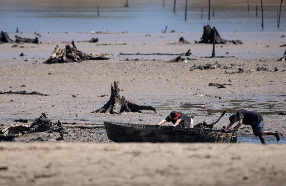 Two boys work to free a fishing boat submerged in mud left in a nearly emptied Wixom Lake in Beaverton on May 21 after the Edenville Dam failed.