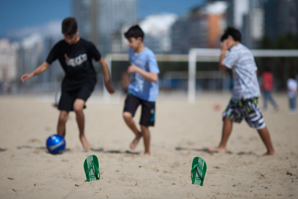 In this July 17, 2012 photo, youths play soccer using Havaianas sandals to mark the goal area on Copacabana beach in Rio de Janeiro, Brazil. In Brazil, literally everyone wears Havaianas, the now world-famous brand of rubber and plastic flip-flops that's celebrating its 50th birthday this year. (AP Photo/Felipe Dana)