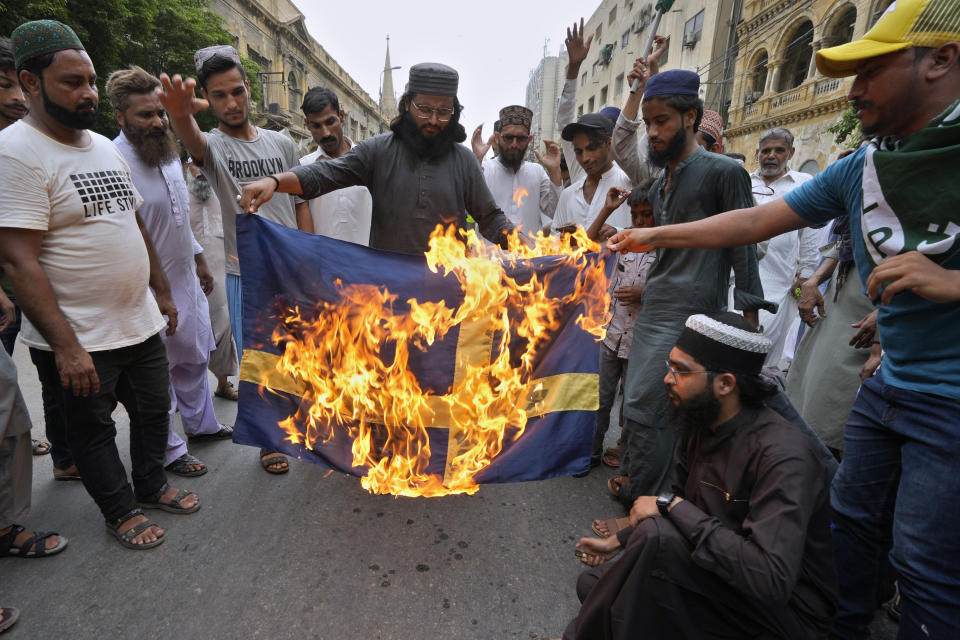 FILE - Supporters of a radical Islamist party 'Tehreek-e-Labaik Pakistan' burn the representation of Swedish flag during a rally to denounce burning of Islam's holy book 'Quran', in Karachi, Pakistan, on July 7, 2023. The targeting of Swedish citizens in an attack in Brussels on the night of Monday, Oct. 16, 2023 has shocked the Scandinavian country, yet the government had been warning for months that Swedes were at greater risk since a recent string of public desecrations of the Quran, Islam's holy book, by a handful of anti-Islam activists. (AP Photo/Fareed Khan, File)