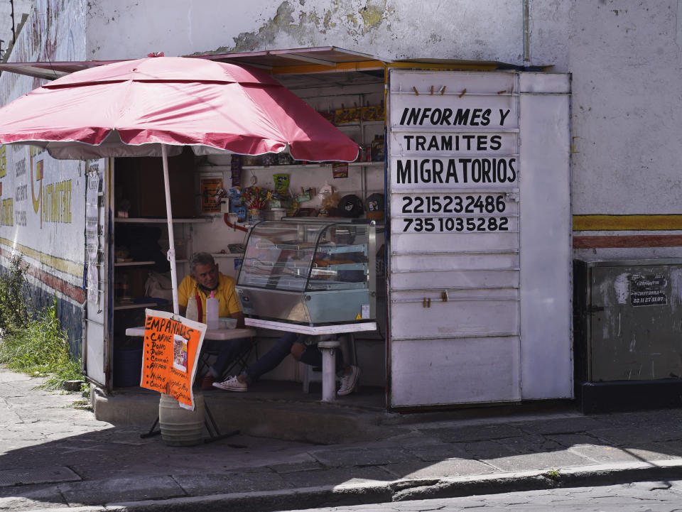 An empanada vendor's stall advertises information, and immigration documents outside the main immigration office in Puebla, Mexico, Sept. 23, 2022. With soaring numbers of migrants entering Mexico, a sprawling network of lawyers, fixers and middlemen has exploded in the country. (AP Photo/Marco Ugarte)