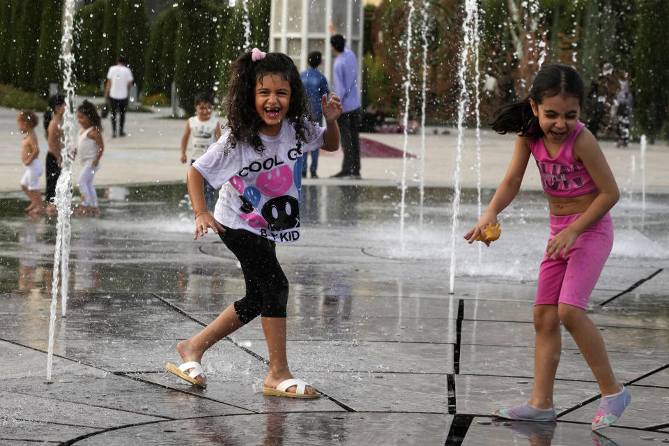 Children enjoy a water fountain at the Ebrahim Park while temperature reaches 38 C (100.4 F) in Tehran, Iran, Tuesday, Aug. 1, 2023. Iran announced a nationwide two-day, Wednesday and Thursday, holiday because of increasing temperatures. (AP Photo/Vahid Salemi)