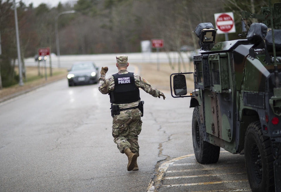 A member of the Rhode Island National Guard Military Police directs a motorist with New York license plates at a checkpoint on I-95 near the border with Connecticut where New Yorkers must pull over and provide contact information and are told to self-quarantine for two weeks, Saturday, March 28, 2020, in Hope Valley, R.I. Rhode Island Gov. Gina Raimondo on Saturday ordered anyone visiting the state to self-quarantine for 14 days and restricted residents to stay at home and nonessential retail businesses to close Monday until April 13 to help stop the spread of the coronavirus. (AP Photo/David Goldman)