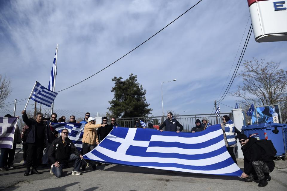 People with Greek flags gather in front of Kastanies border gate at the Greek-Turkish border, Sunday, March 1, 2020. Migrants and refugees were trying to enter Greece by land and by sea Sunday despite Greece making clear it would not allow anyone in, after Turkey officially declared its western borders open to those hoping to head into the European Union. (AP Photo/Giannis Papanikos)