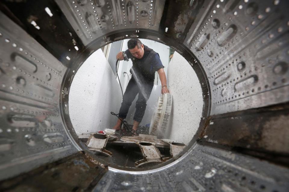 保潔工坊老闆羅緯文在客人家的陽台清洗洗衣機，透過拆解下的洗衣槽看他工作，另有一番風景。