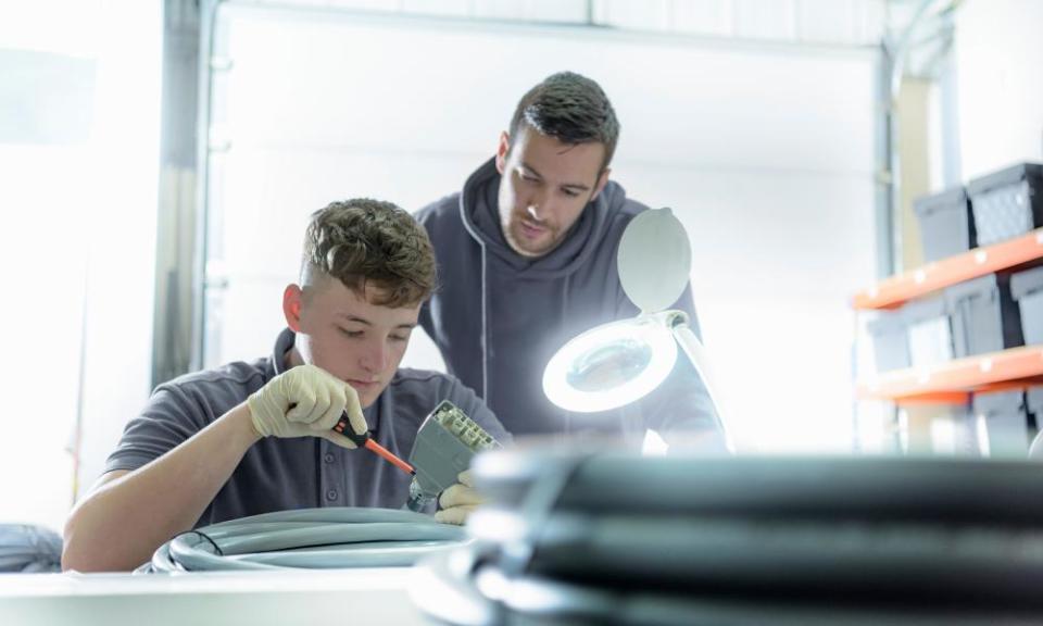 An apprentice electrical engineer under instruction in a cable-finishing factory