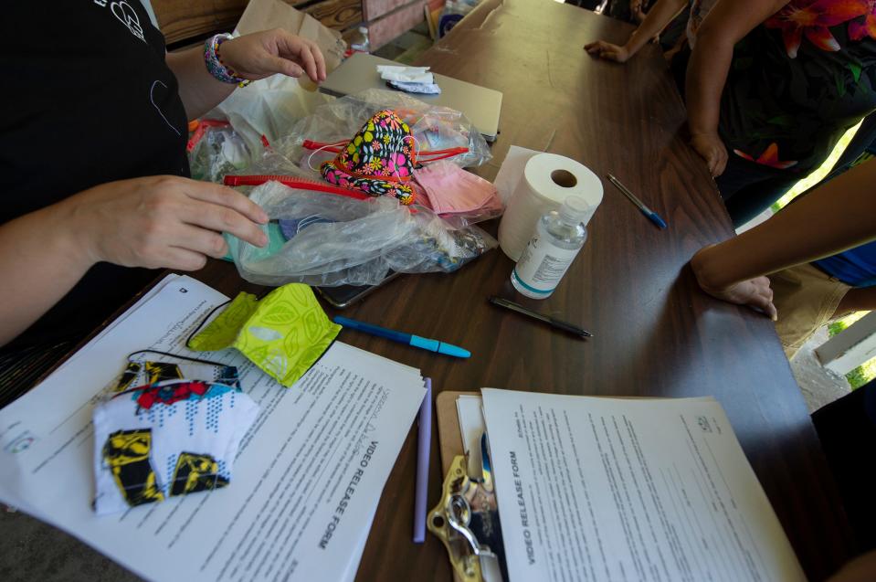 Monica Soto of El Pueblo, a nonprofit specializing in immigration legal services, is ready with masks and hand sanitizer for people in line for school supplies during a school supply distribution at Trinity Mission Center in Forest, Miss., Saturday, July 11, 2020. The event was hosted by El Pueblo in cooperation with Sugartown Riders Motorcycle Club from Kosciusko, Miss. In August 2019, the Latino community in Forest was hit hard by ICE raids at local poultry plants. According to El Pueblo's Facebook page, the masks were made by Mujeres Unidas (United Women), in support of poultry factory workers and all essential workers.