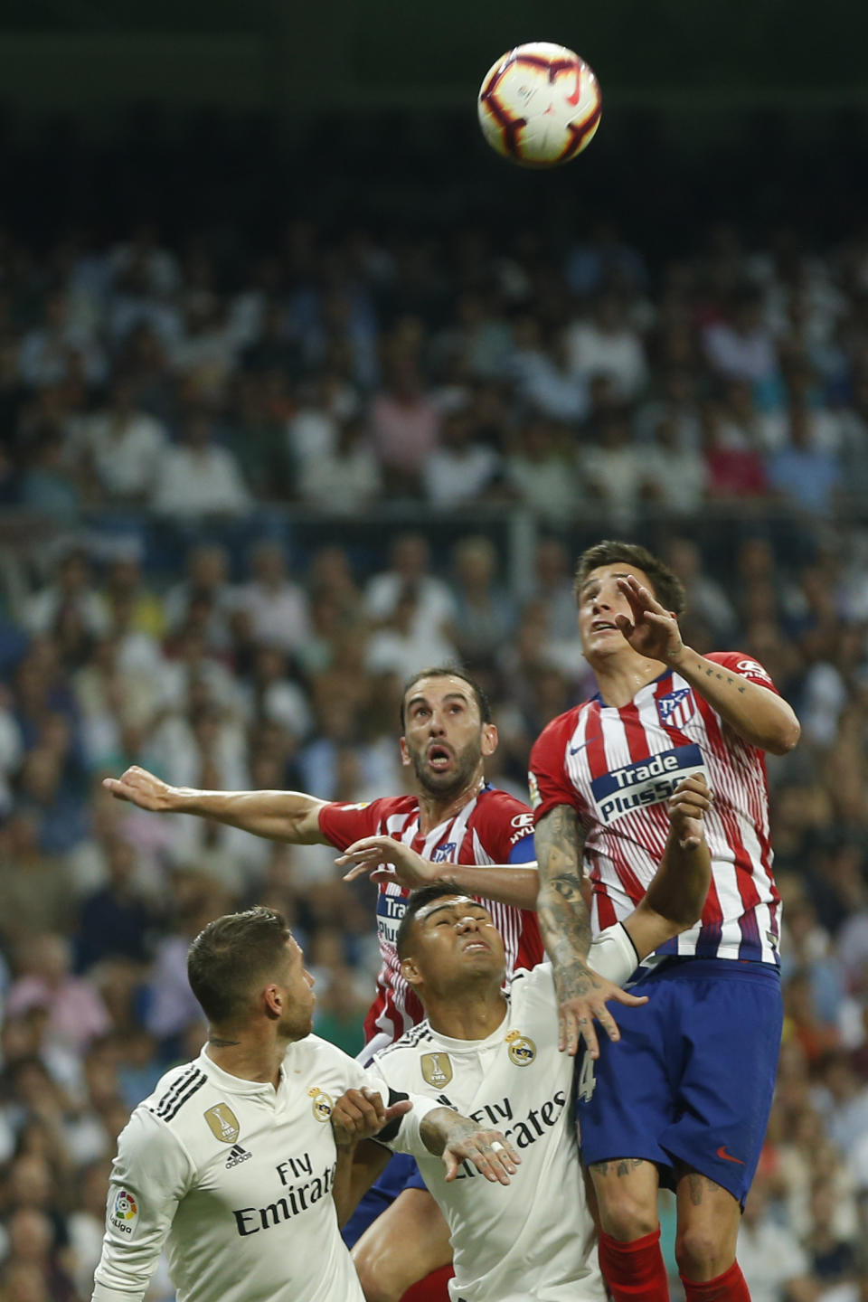 Atletico Madrid's Jose Maria Gimenez, top right, and Diego Godin, top left, vies for a high ball with Real Madrid's Casemiro and Sergio Ramos, left, during a Spanish La Liga soccer match between Real Madrid and Atletico Madrid at the Santiago Bernabeu stadium in Madrid, Spain, Saturday, Sept. 29, 2018. (AP Photo/Paul White)