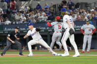 Washington Nationals shortstop CJ Abrams (5) reaches first base on a single as Texas Rangers starting pitcher Jon Gray, right front, watches first baseman Nathaniel Lowe defend the bag in the first inning of a baseball game in Arlington, Texas, Tuesday, April 30, 2024. Umpire Edwin Jimenez, left, looks on at the play. (AP Photo/Tony Gutierrez)