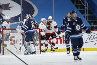 Ottawa Senators' Evgenii Dadonov, center left, and Nick Paul celebrate Dadonov's goal against Winnipeg Jets goaltender Connor Hellebuyck (37) during the second period of an NHL hockey game Saturday, Jan. 23, 2021, in Winnipeg, Manitoba. (John Woods/The Canadian Press via AP)