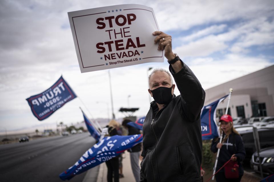 FILE - Supporters of President Donald Trump hold signs as they stand outside of the Clark County Elections Department in North Las Vegas, Nov. 7, 2020. According to a bipartisan report released Tuesday, Feb. 6, 2024, that calls for greater transparency and steps to make voting easier, a “tumultuous period of domestic unrest” combined with a complicated and highly decentralized election system has led to a loss of faith in election results among some in the U.S. (AP Photo/Wong Maye-E, File)