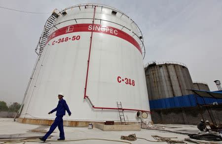 An employee walks past oil tanks at a Sinopec refinery in Wuhan, Hubei province, April 25, 2012. REUTERS/Stringer/File Photo