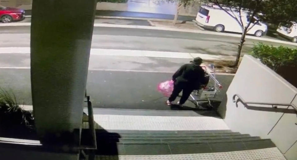 CCTV showing person in black walking away with grocery bags. 