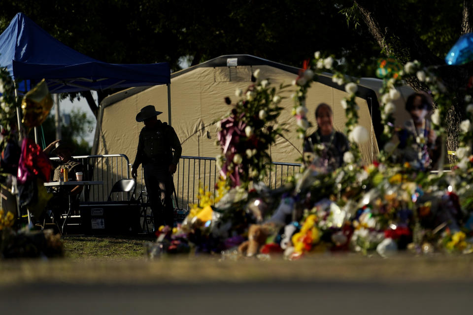 FILE - A Texas Department of Public Safety officer keeps watch on June 3, 2022, in Uvalde, Texas, near a memorial outside Robb Elementary School created to honor the victims killed in last a school shooting. As public pressure mounts for more information on the deadly Uvalde school shooting, some are concerned that Texas officials will use a legal loophole to block records from being released — even to the victims' families — once the case is closed. (AP Photo/Eric Gay, File)