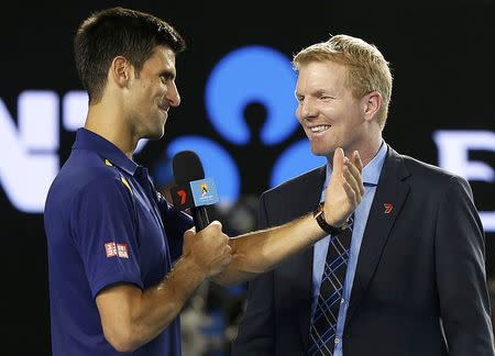 Serbia's Novak Djokovic (L) takes the microphone from former tennis player Jim Courier while being interviewed after winning his semi-final match against Switzerland's Roger Federer at the Australian Open tennis tournament at Melbourne Park, Australia, January 28, 2016. REUTERS/Tyrone Siu
