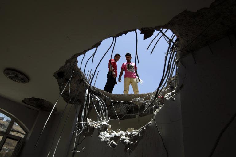 Yemenis peer down through a hole in the roof of a house in Sanaa which was damaged in an air strike by Saudi-led coalition warplanes on April 21, 2015