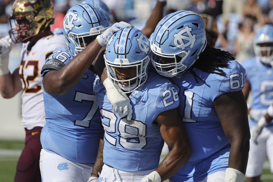 North Carolina running back Omarion Hampton (28) is congratulated by offensive linemen Diego Pounds (61) and William Barnes (76) following a touchdown run during the second quarter of an NCAA college football game against Minnesota, Saturday, Sept. 16, 2023, in Chapel Hill, N.C. (AP Photo/Reinhold Matay)