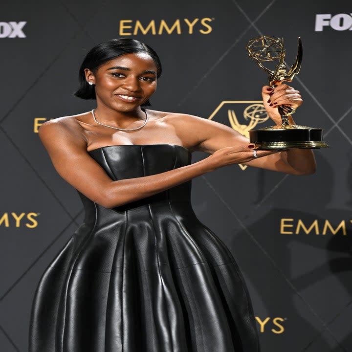 ayo holding up her award