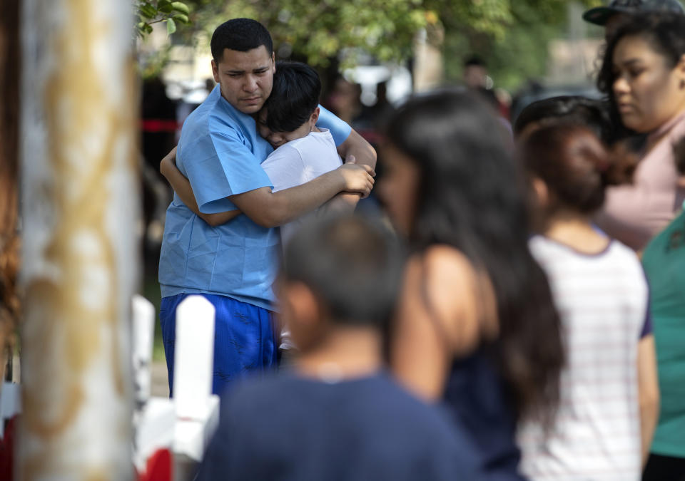 In this Sunday, Aug. 26, 2018, photo, Marcos Contreras, left, hugs another person near wood crosses at the scene of a fatal fire that killed several people including multiple children in Chicago. (Erin Hooley/Chicago Tribune via AP)