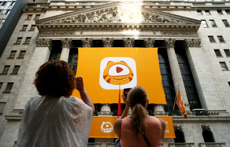 People take pictures of the Huya Inc. logo ahead of the company's IPO at the New York Stock Exchange (NYSE) in New York