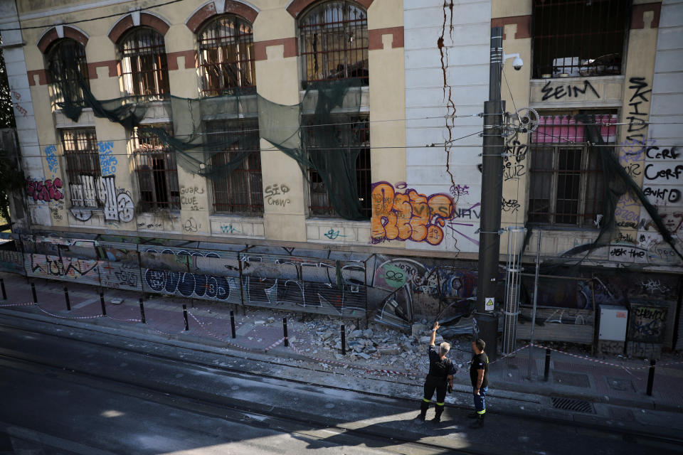 Pictured are firefighters looking at a damaged abandoned building following an earthquake, in Piraeus, Greece.