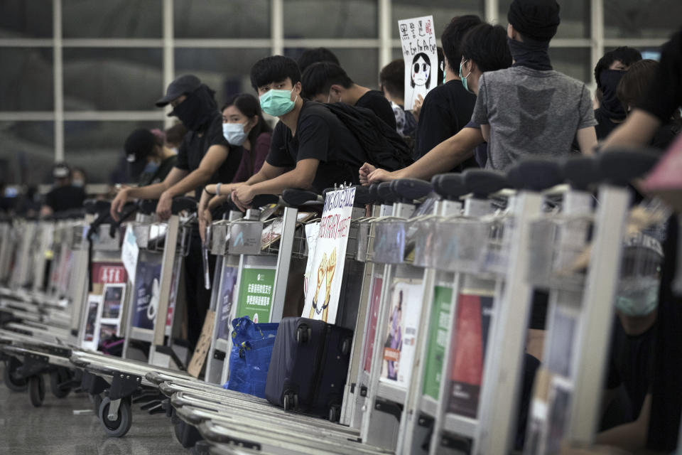 Protesters use luggage trolleys to block the departure gates during a demonstration at the Airport in Hong Kong, Tuesday, Aug. 13, 2019. Protesters severely crippled operations at Hong Kong's international airport for a second day Tuesday, forcing authorities to cancel all remaining flights out of the city after demonstrators took over the terminals as part of their push for democratic reforms. (AP Photo/Vincent Thian)