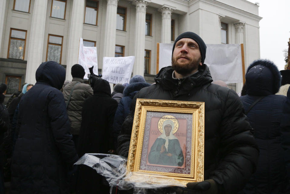 Believers of the Ukrainian Orthodox Church of Moscow Patriarchy protest against the creation of a Ukrainian independent church, in front of the parliament building in Kiev, Ukraine, Thursday, Dec. 20, 2018. Writing on the poster reads "We pray God to give you mind." (AP Photo/Efrem Lukatsky)