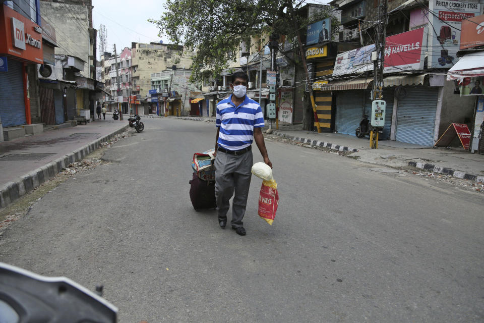 A man with luggage walks looking for transportation during reimposed weekend lockdown to prevent the spread of coronavirus in Jammu, India, Sunday, Aug 2, 2020. India is the third hardest-hit country by the pandemic in the world after the United States and Brazil. (AP Photo/Channi Anand)