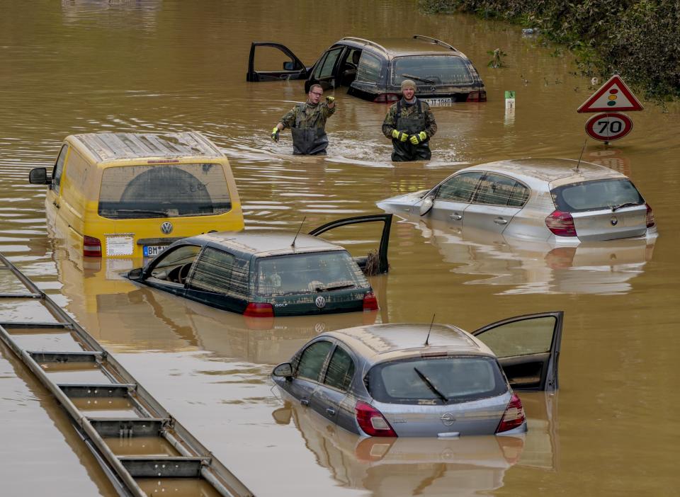 FILE - In this file photo dated Saturday, July 17, 2021, people check for victims in flooded cars on a road in Erftstadt, Germany, following heavy rainfall that broke the banks of the Erft river, causing massive damage. The German government on Tuesday Aug. 10, 2021, has agreed to provide 58 billion euros (dollars 68 billion US) to help rebuild regions hit by devastating floods last month. (AP Photo/Michael Probst, FILE)