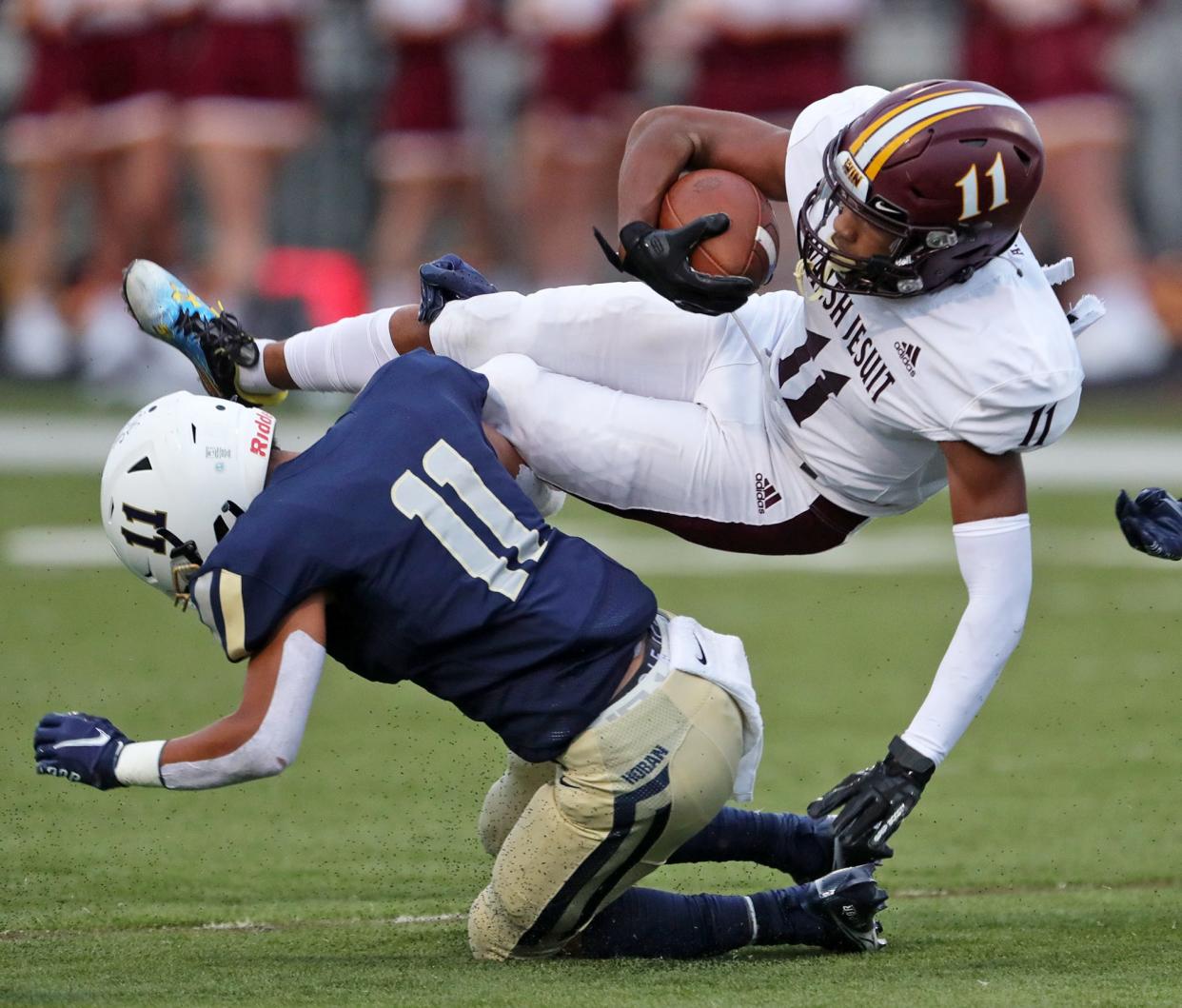 Walsh Jesuit wide receiver Trey Bell, top is tripped up just short of the first down by Hoban defensive back Tysen Campbell during the first half of a high school football game, Friday, Sept. 3, 2021, in Akron, Ohio.