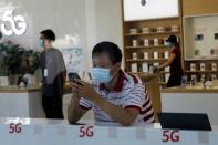 Man checks a mobile phone inside a Huawei store at a shopping mall in Beijing