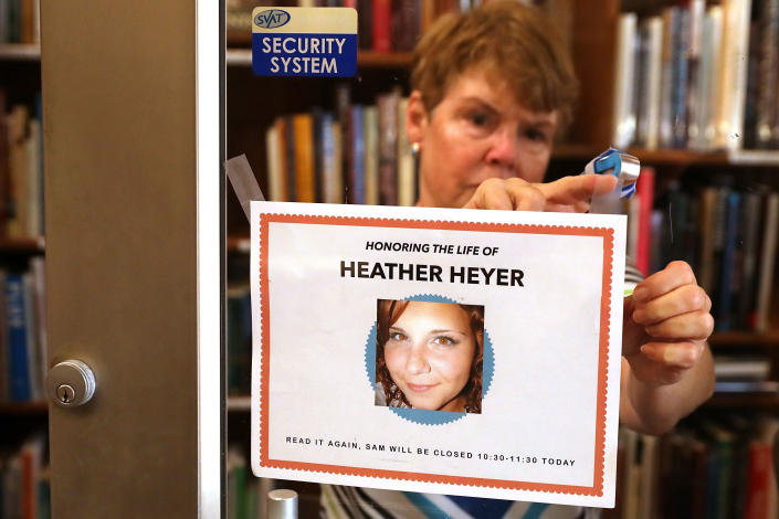 A person&amp;nbsp;tapes a note to the front door of a bookstore to announce that it will close during the memorial service for Heather Heyer.
