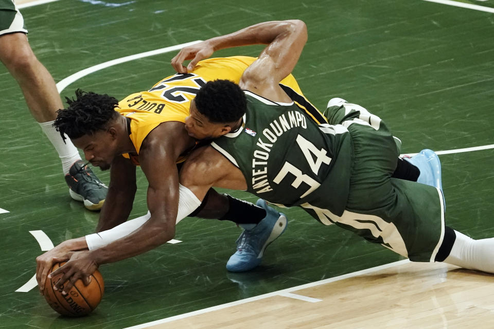 Miami Heat's Jimmy Butler and Milwaukee Bucks' Giannis Antetokounmpo battle for a loose ball during the second half of Game 1 of their NBA basketball first-round playoff series Saturday, May 22, 2021, in Milwaukee. (AP Photo/Morry Gash)