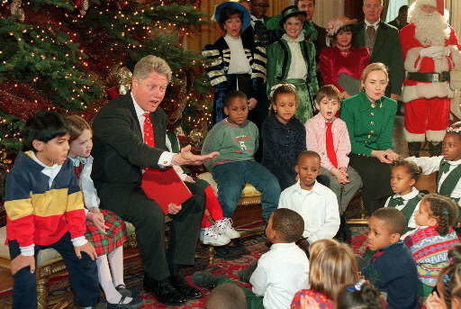 President Clinton, joined by first lady Hillary Rodham Clinton and Santa Claus, gestures while reading "Twas the Night Before Christmas" to Washington area children, Friday Dec. 22, 1995 at the White House. The president and first lady hosted the children with the reading and the singing of Christmas carols.(AP Photos/J Scott Applewhite)
