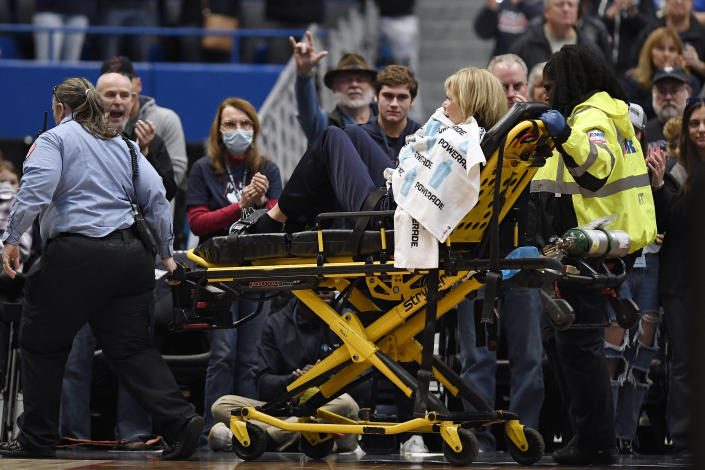 Associate Head Coach Chris Dailey is taken off the basketball court on a stretcher before an NCAA basketball game against North Carolina State, Sunday, Nov. 20, 2022, in Hartford, Conn. Dailey experienced a medical emergency during the national anthem. (AP Photo/Jessica Hill)