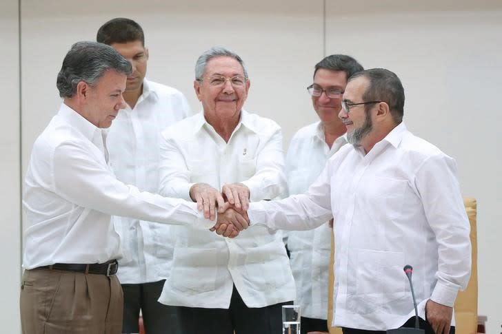 Cuba's President Raul Castro (C) stands as Colombia's President Juan Manuel Santos (L) and FARC rebel leader Rodrigo Londono, better known by the nom de guerre Timochenko, shake hands in Havana, September 23, 2015.  REUTERS/Alexandre Meneghini 