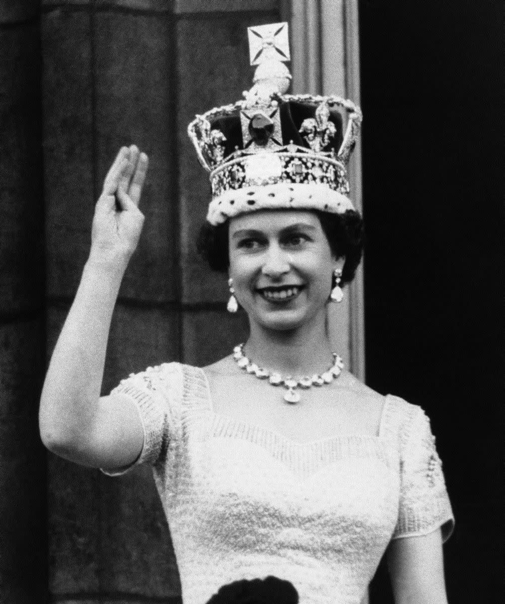 Queen Elizabeth II, wearing the Imperial Crown, smiles and waves to crowd from balcony of Buckingham Palace on June 3, 1953 in London, on returning from Westminster Abbey following her coronation.