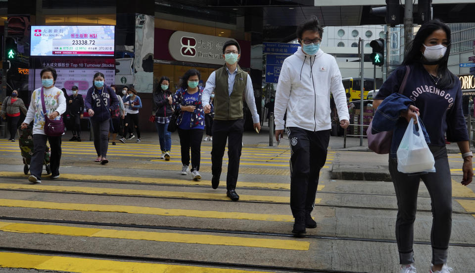 People wearing face masks walk at a down town street in Hong Kong Wednesday, March 25, 2020. For most, the coronavirus causes only mild or moderate symptoms, such as fever and cough. But for a few, especially older adults and people with existing health problems, it can cause more severe illnesses, including pneumonia. (AP Photo/Vincent Yu)