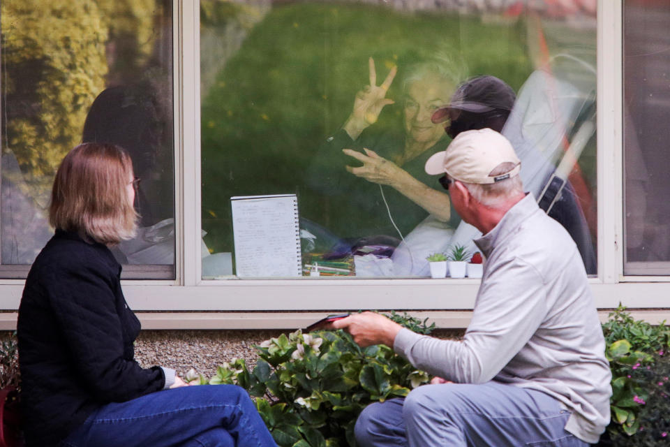 Judie Shape, 81, who tested positive for coronavirus, acknowledges press photographers gathered outside as her daughter Lori Spencer and husband Michael Spencer visit outside her room at Care Center of Kirkland, the Seattle-area nursing home which is one of the epicenters of the coronavirus (COVID-19) outbreak, in Kirkland, Washington, U.S. March 17, 2020.  REUTERS/Jason Redmond