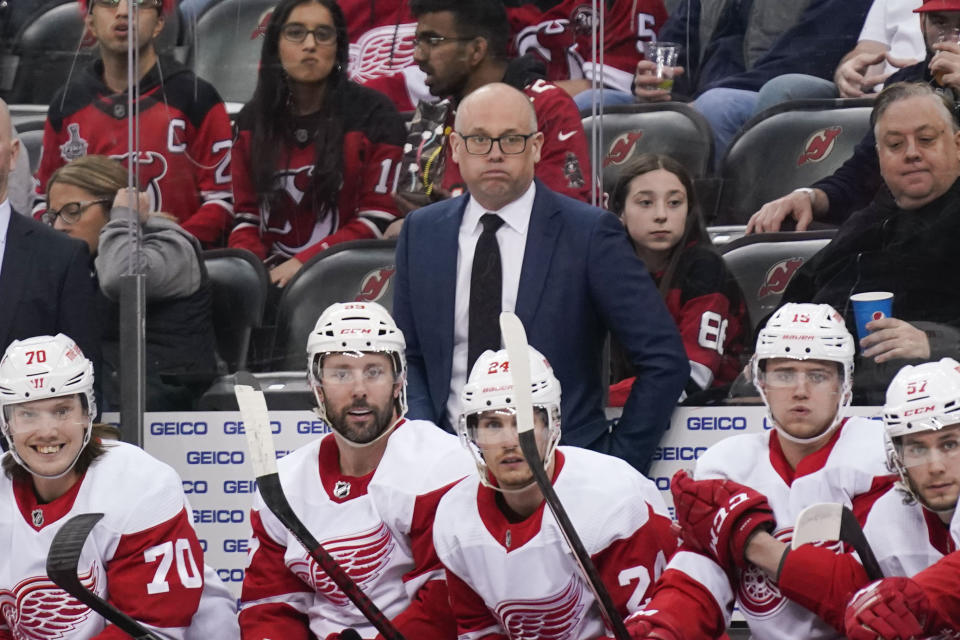 Detroit Red Wings head coach Jeff Blashill, center, looks over the ice during the first period of an NHL hockey game against the New Jersey Devils in Newark, N.J., Friday, April 29, 2022. (AP Photo/Seth Wenig)