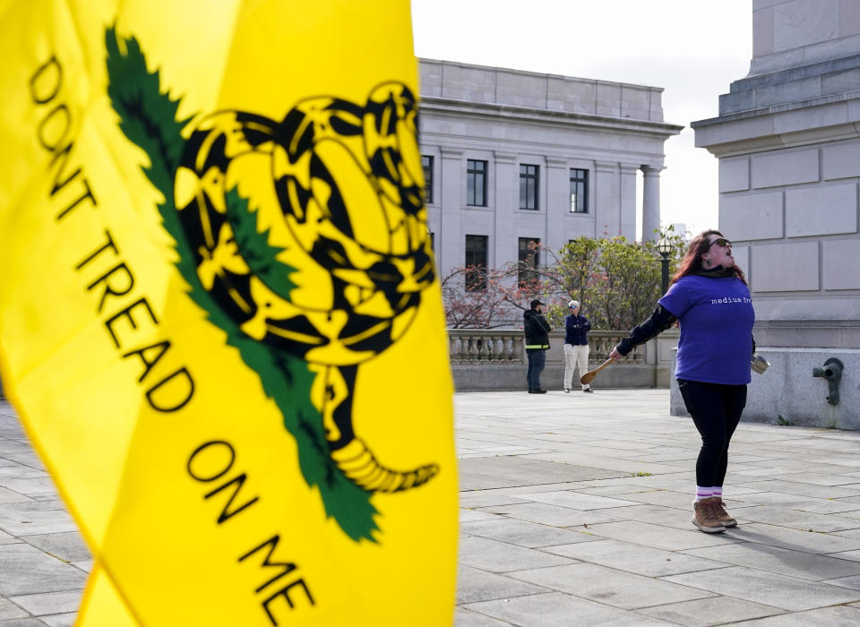 Ryan Olski yells and bangs on a pot in front of a Gadsden flag while a group protests before the signing of firearms regulation bills by Washington Gov. Jay Inslee, Tuesday, April 25, 2023, outside the Capitol in Olympia, Wash. (AP Photo/Lindsey Wasson)