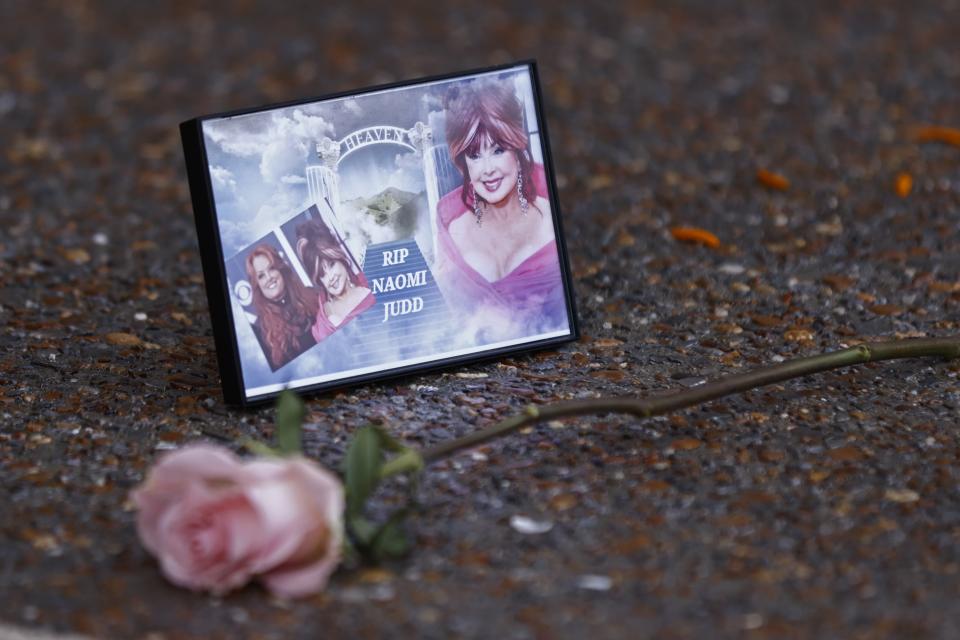 A photograph of Naomi Judd lays with a rose outside the Country Music Hall of Fame before the medallion ceremony on Sunday, May 1, 2022, in Nashville, Tenn. (Photo by Wade Payne/Invision/AP)