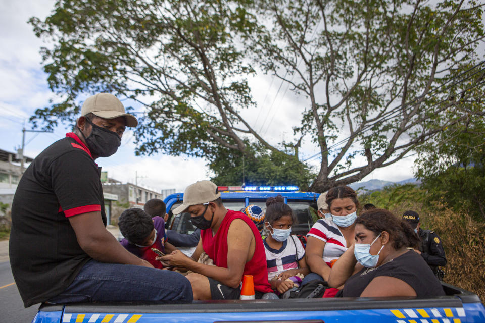 Honduran migrants sit in the bed of a police vehicle after they were detained in Chiquimula, Guatemala, Tuesday, Jan. 19, 2021. A once large caravan of Honduran migrants that pushed its way into Guatemala last week had dissipated by Tuesday in the face of Guatemalan security forces. (AP Photo/Oliver de Ros)