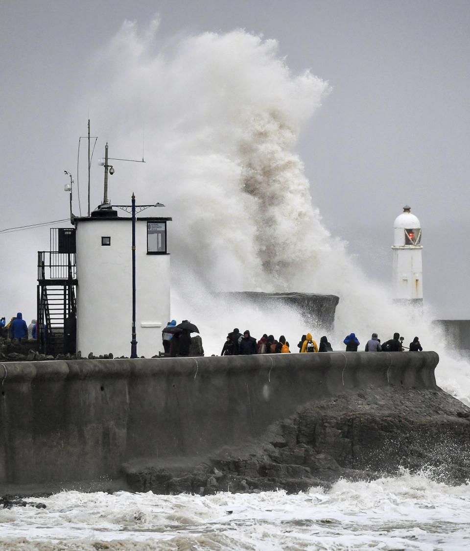 People watch waves and rough seas pound against the harbour wall at Porthcawl in Wales, as Storm Dennis sweeps across the country, Saturday Feb. 15, 2020. Enormous waves are churning across the North Atlantic as Britain braces for a second straight weekend of wild winter weather and flooding. (Ben Birchall/PA via AP)