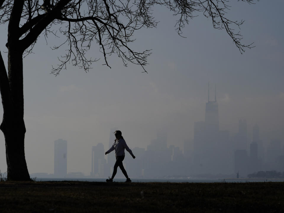 A person walks along the shore of Lake Michigan Tuesday, Feb. 27, 2024, in Chicago. A warm front is sweeping spring-like weather across a large swath of the country in what is usually one of the coldest months of the year. (AP Photo/Kiichiro Sato)